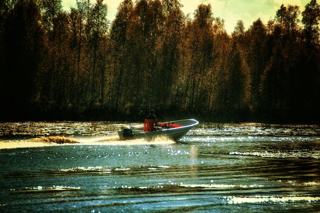 Premium Photo | Man driving motorboat in river against trees Jack Rides In A Motorboat Against A River Current